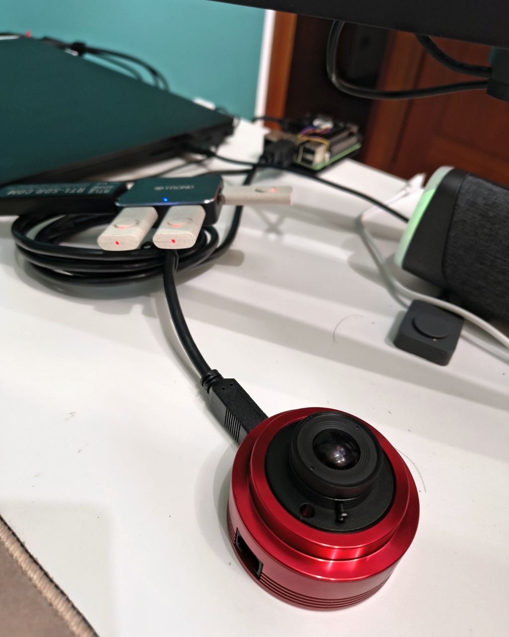 Camera ZWO rossa con obiettivo e collegamento USB all’hub